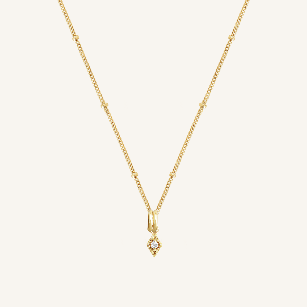 A delicate necklace featuring a small diamond charm pendant suspended from a gold-tone chain.
