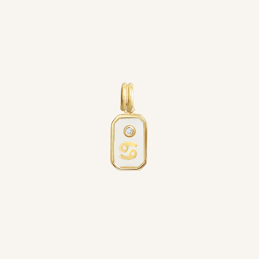 A gold rectangular shaped charm with the Cancer zodiac symbol on it, designed with an iridescent finish.