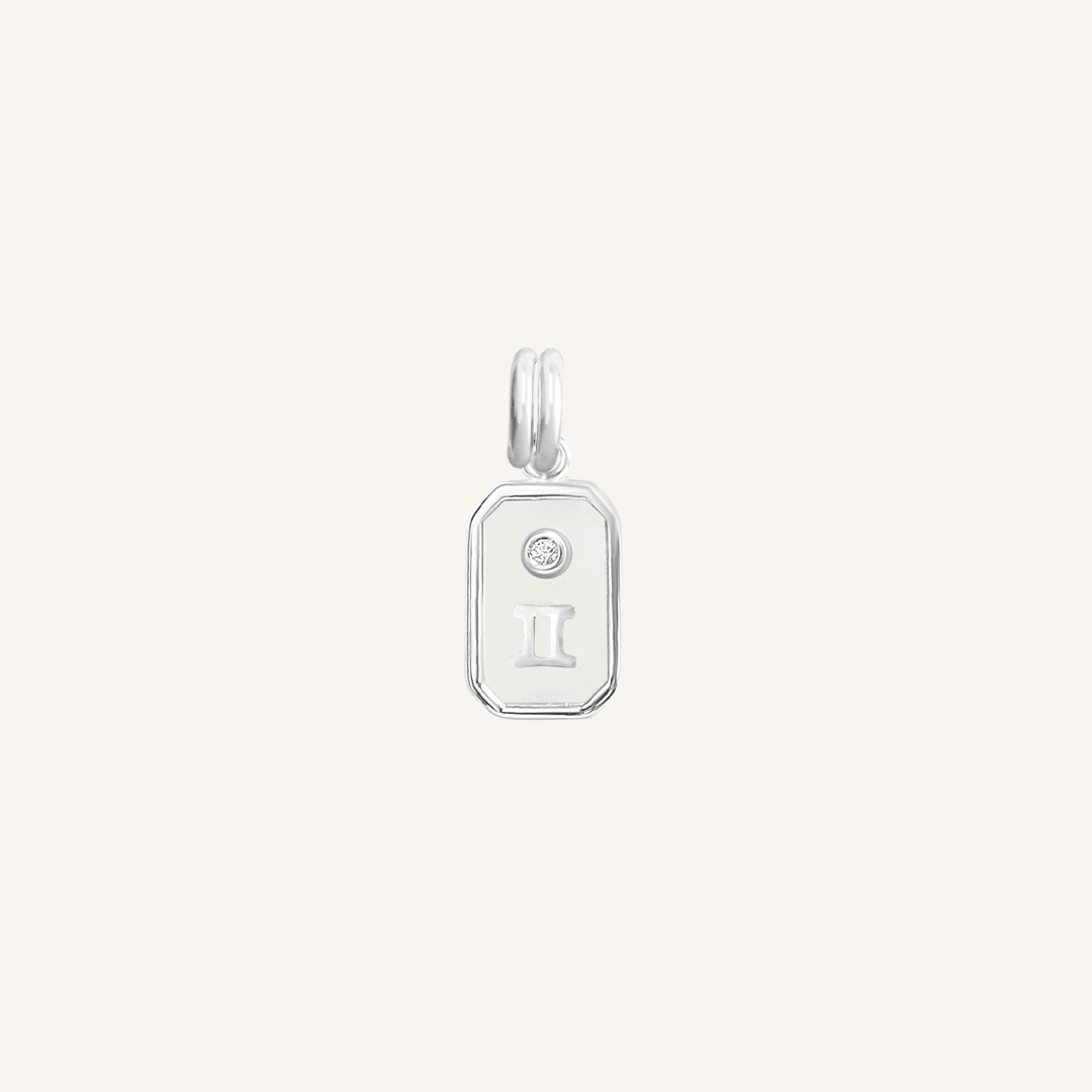 A silver rectangular shaped charm with the Gemini zodiac symbol on it, designed with an iridescent finish.