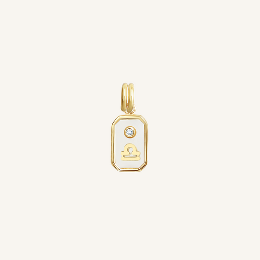 A gold rectangular shaped charm with the Libra zodiac symbol on it, designed with an iridescent finish.
