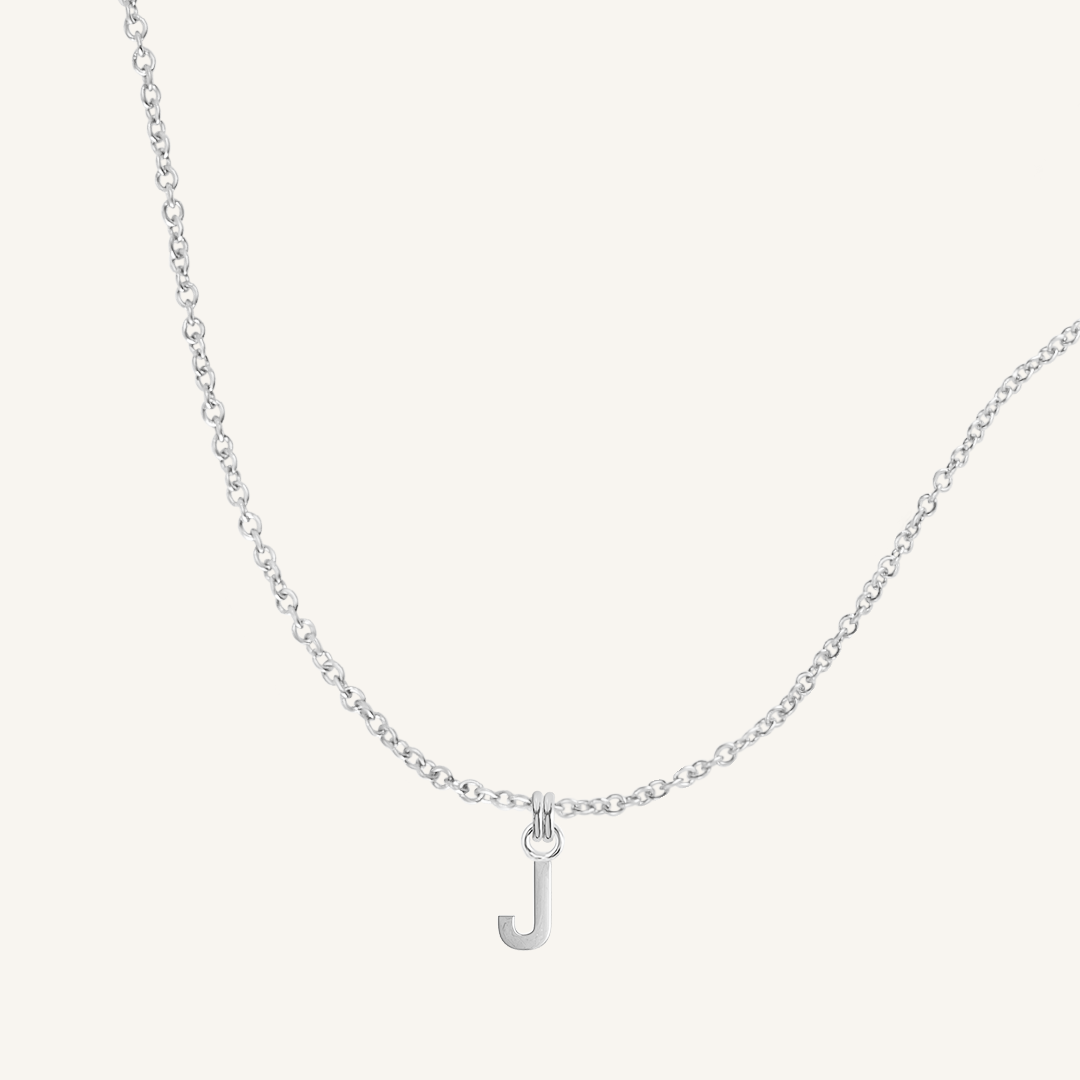 Silver necklace with a 'J' pendant on a light gray background