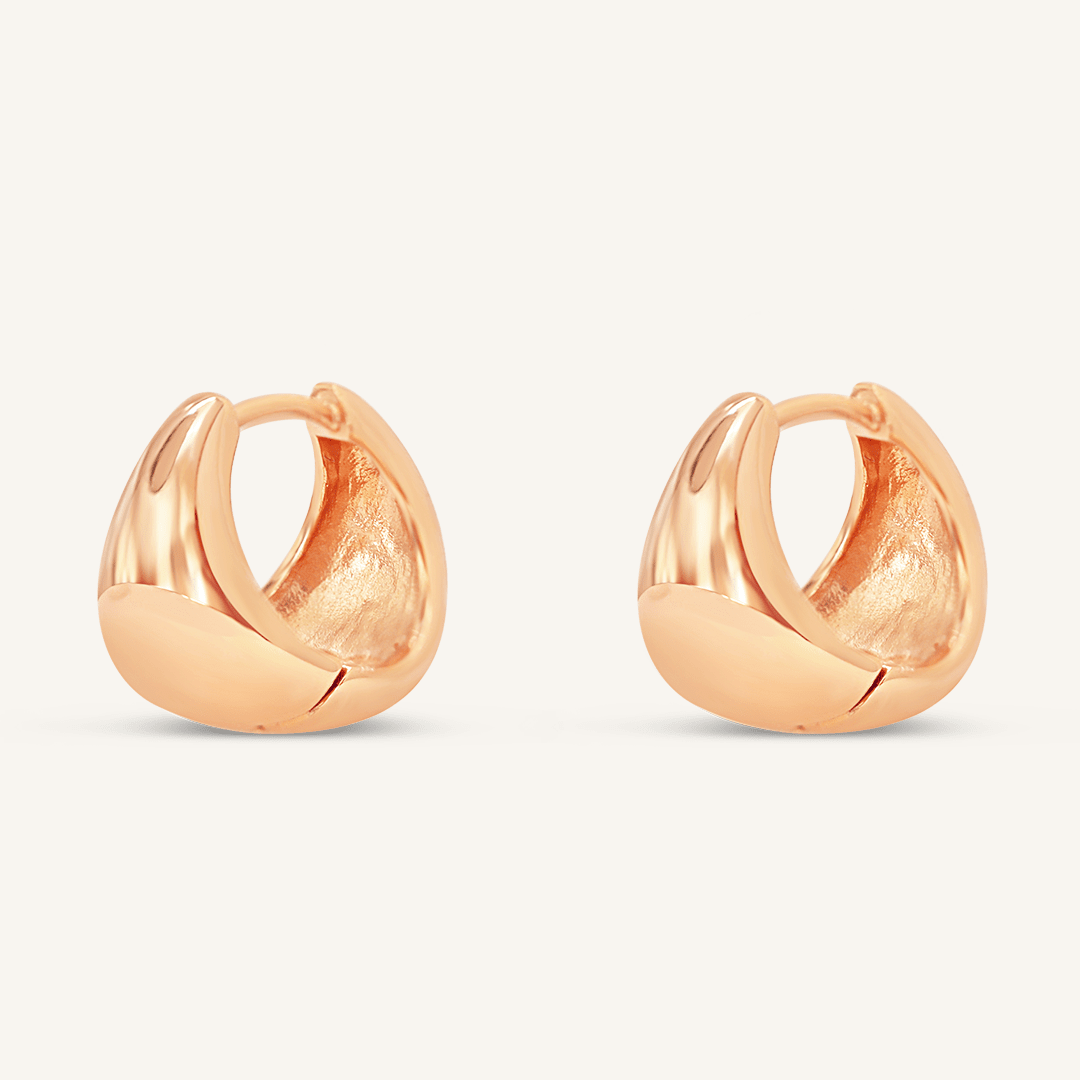 A pair of rose huggie hoop earrings on a white background.