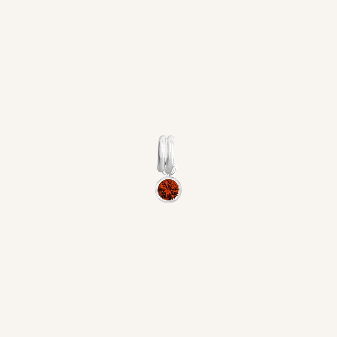 Round silver charm with bezel-set garnet cubic zirconia representing the January birthstone.