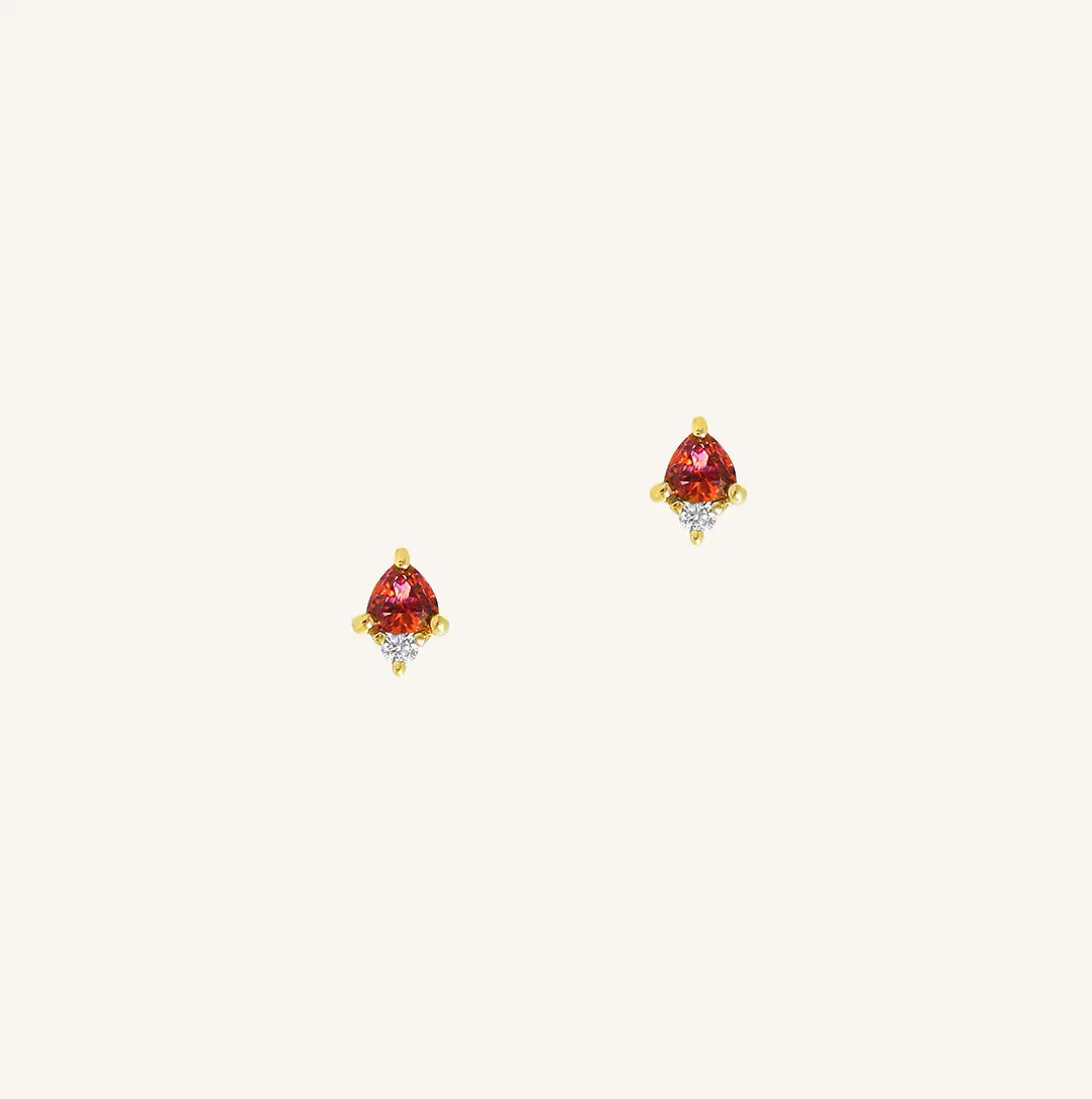 A gold pair of stud earrings featuring a red cubic zirconia, representing January.