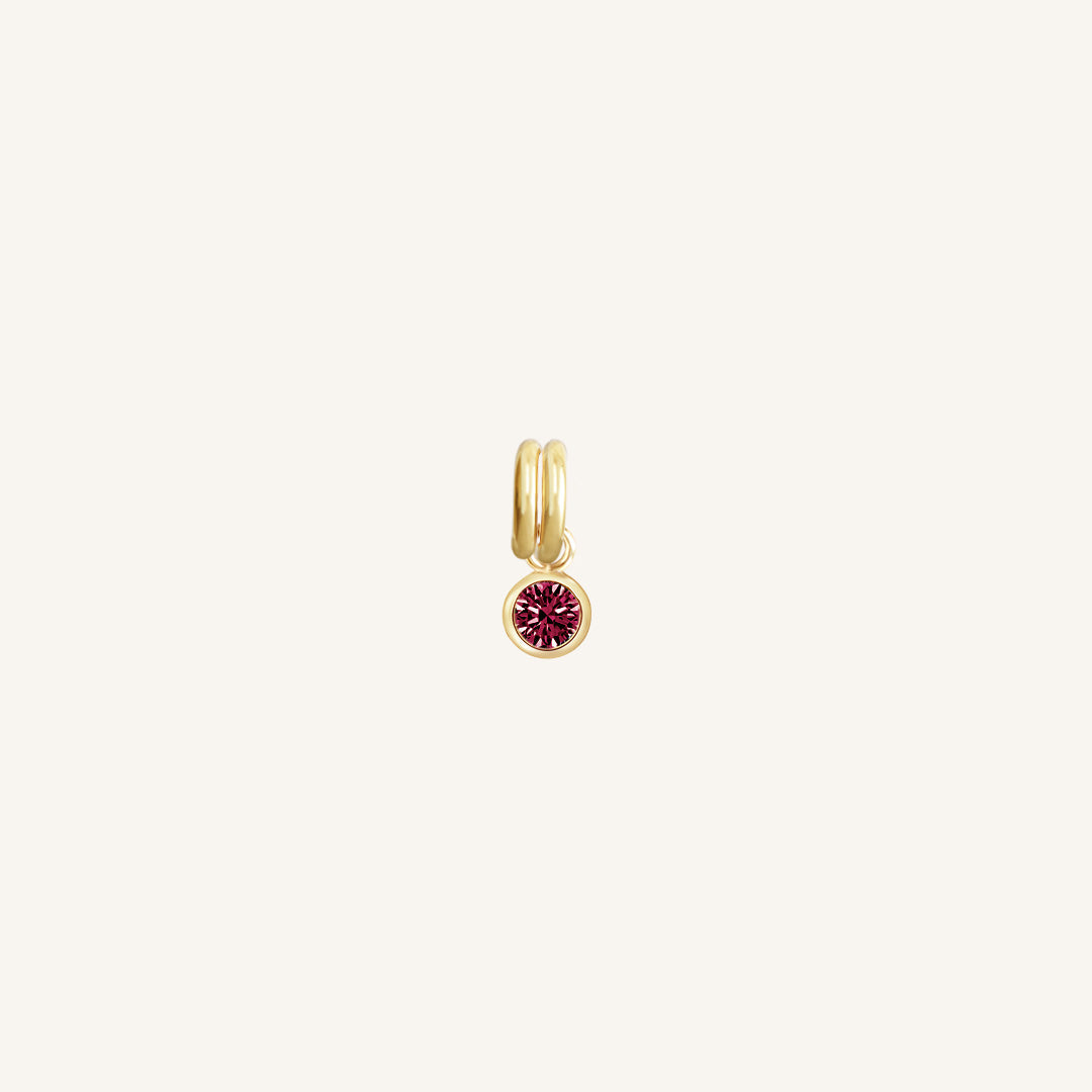 Round gold charm with bezel-set ruby cubic zirconia representing the July birthstone.