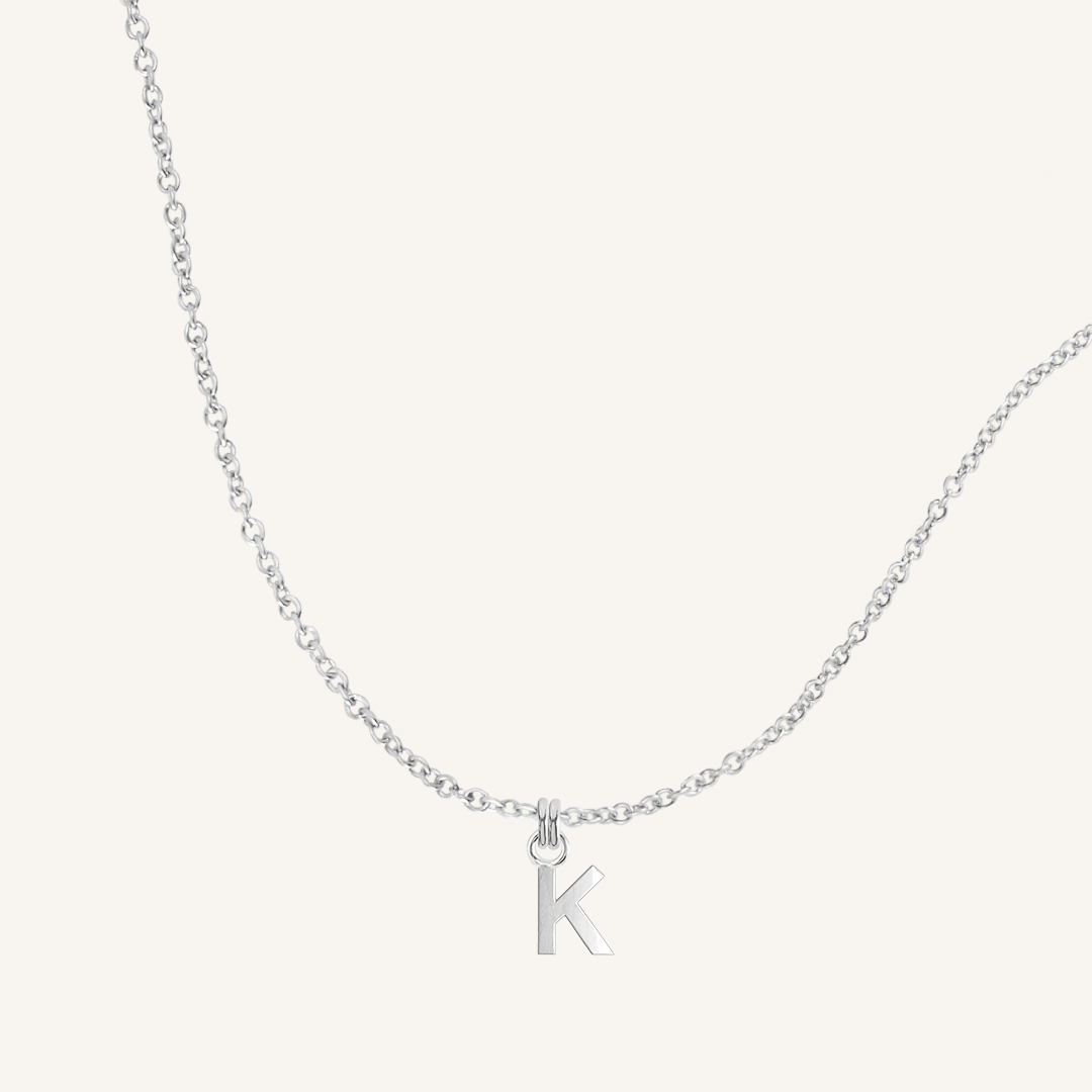 Silver necklace with a 'K' pendant on a light gray background