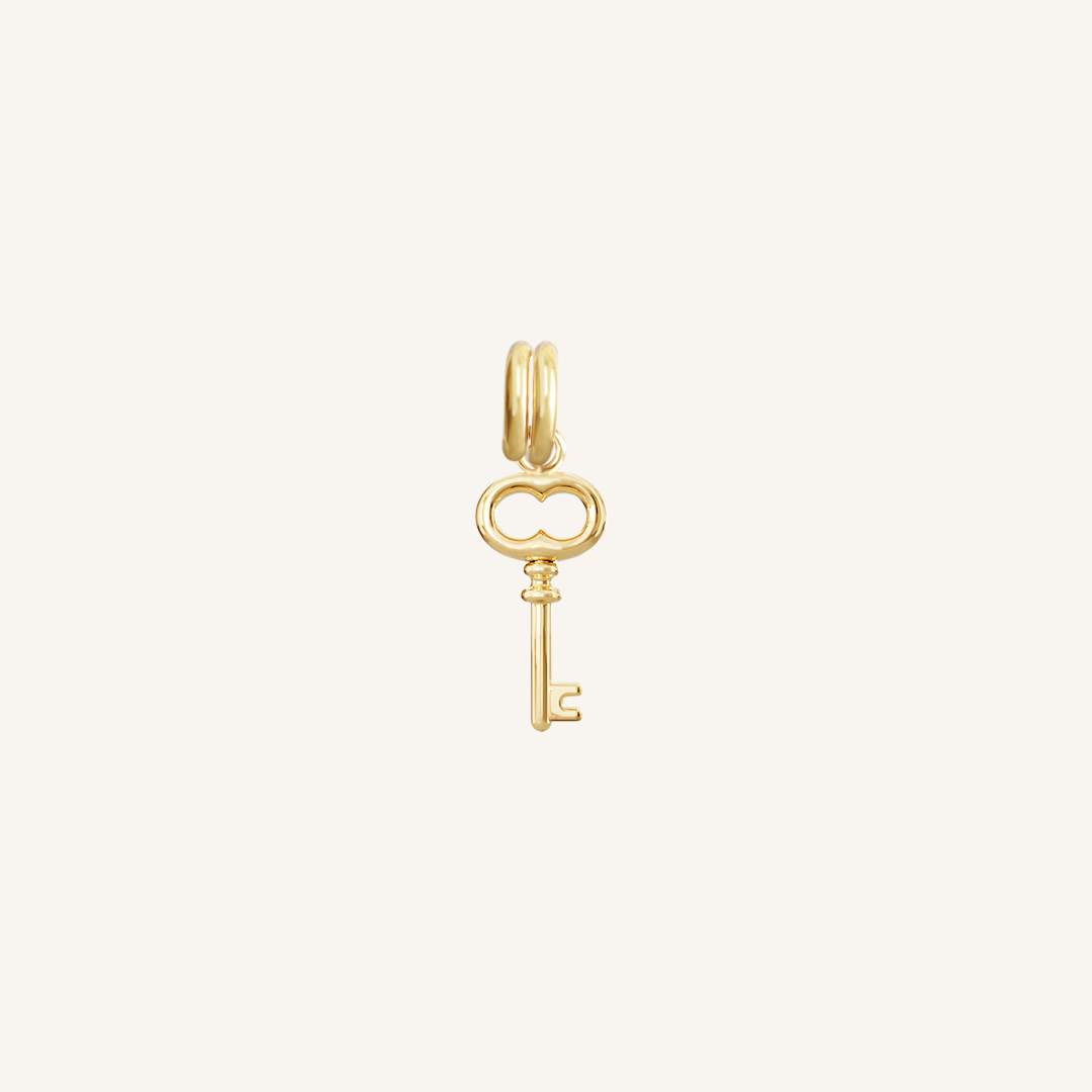A gold key charm on a plain background