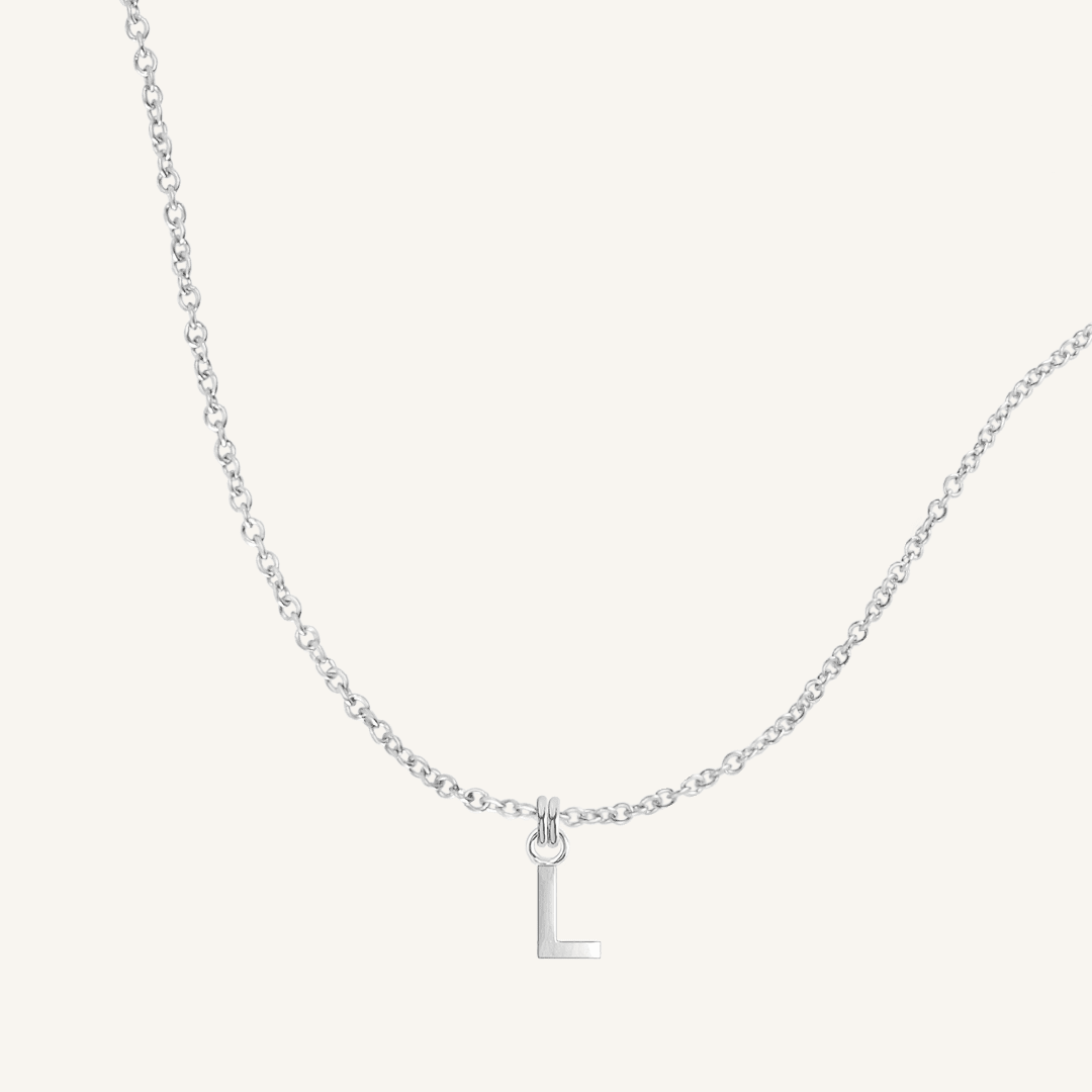 Silver necklace with a 'L' pendant on a light gray background