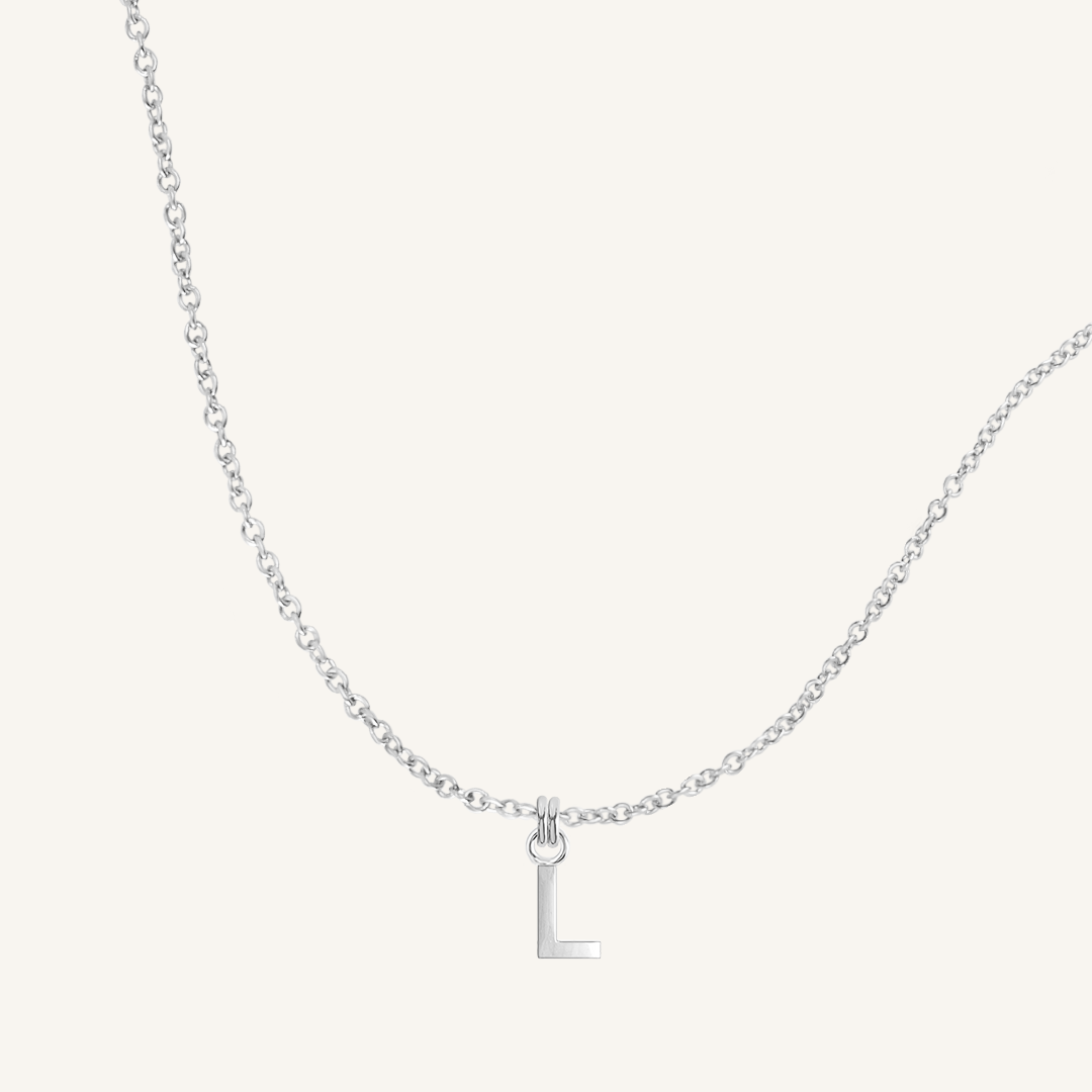 Silver necklace with a 'L' pendant on a light gray background