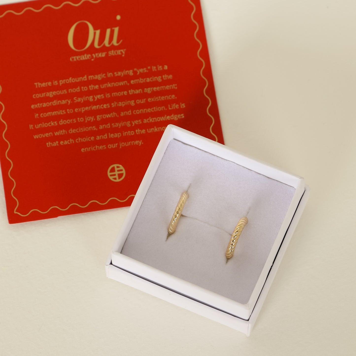 gold delicate hoops with a twist design on white box