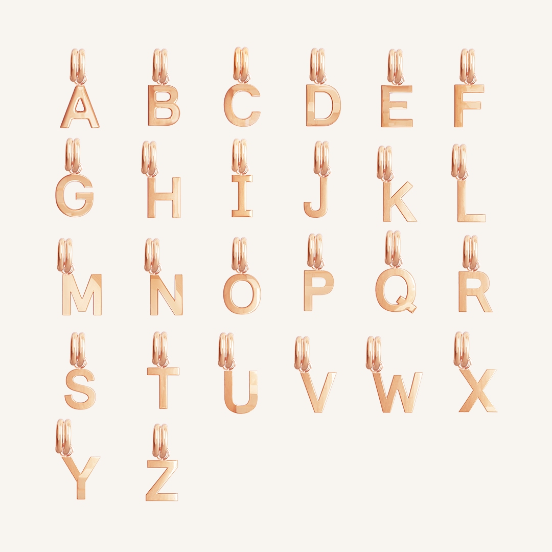 All letter charms in rose gold on plain background