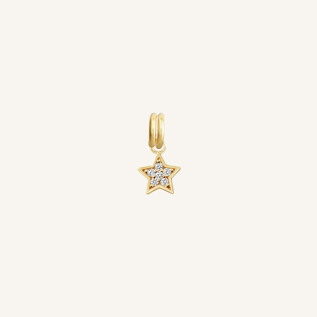A gold coloured charm in the shape of a star with a small cubic zirconias, designed to be attached to a bracelet or chain.