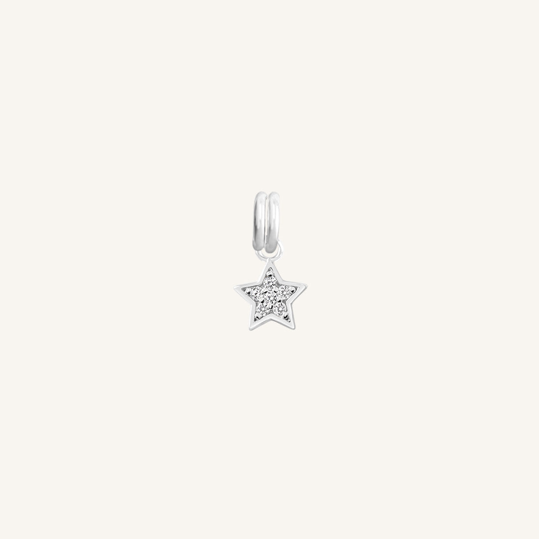 A silver coloured charm in the shape of a star with a small cubic zirconias, designed to be attached to a bracelet or chain.