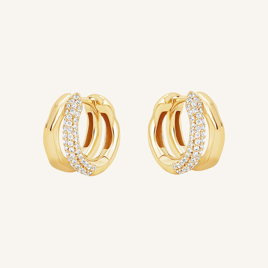 A pair of gold-coloured hoop earrings with a huggie design, featuring a layered look and pave white stones on one side.