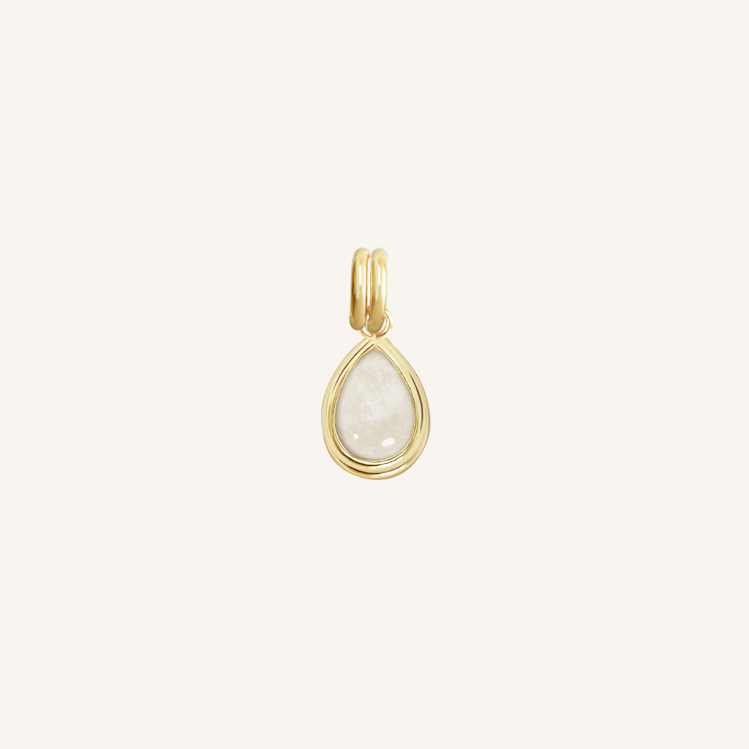 A gold charm with a teardrop-shaped moonstone