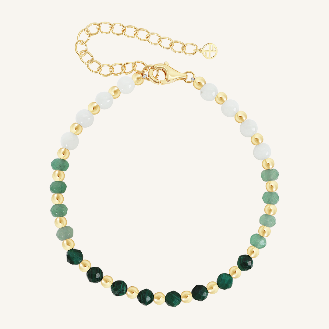 A beaded bracelet with green malachite ombre and gold metal accents, featuring an extender chain.