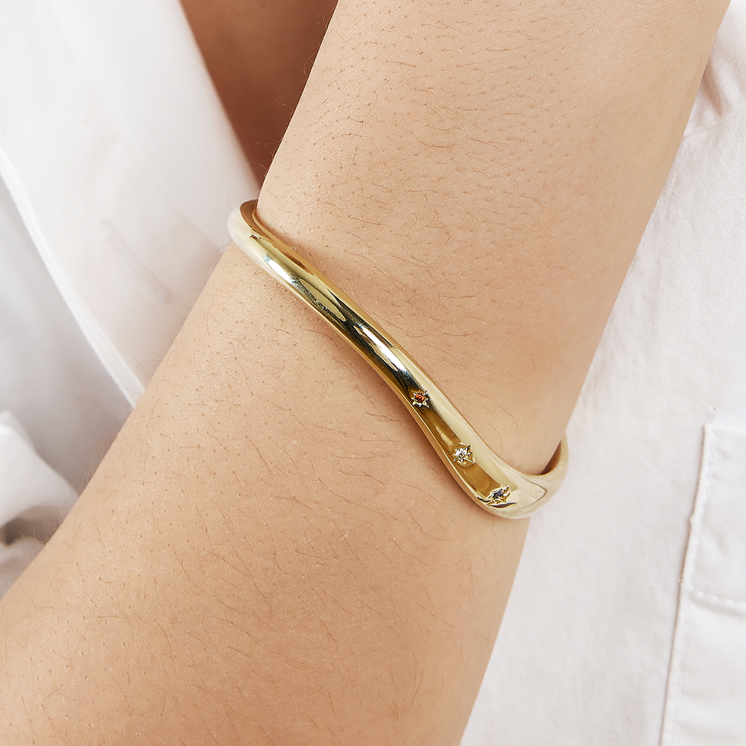 Gold cuff asymmetrical in shape with Navy, white and red cubic zirconias in a row on wrist