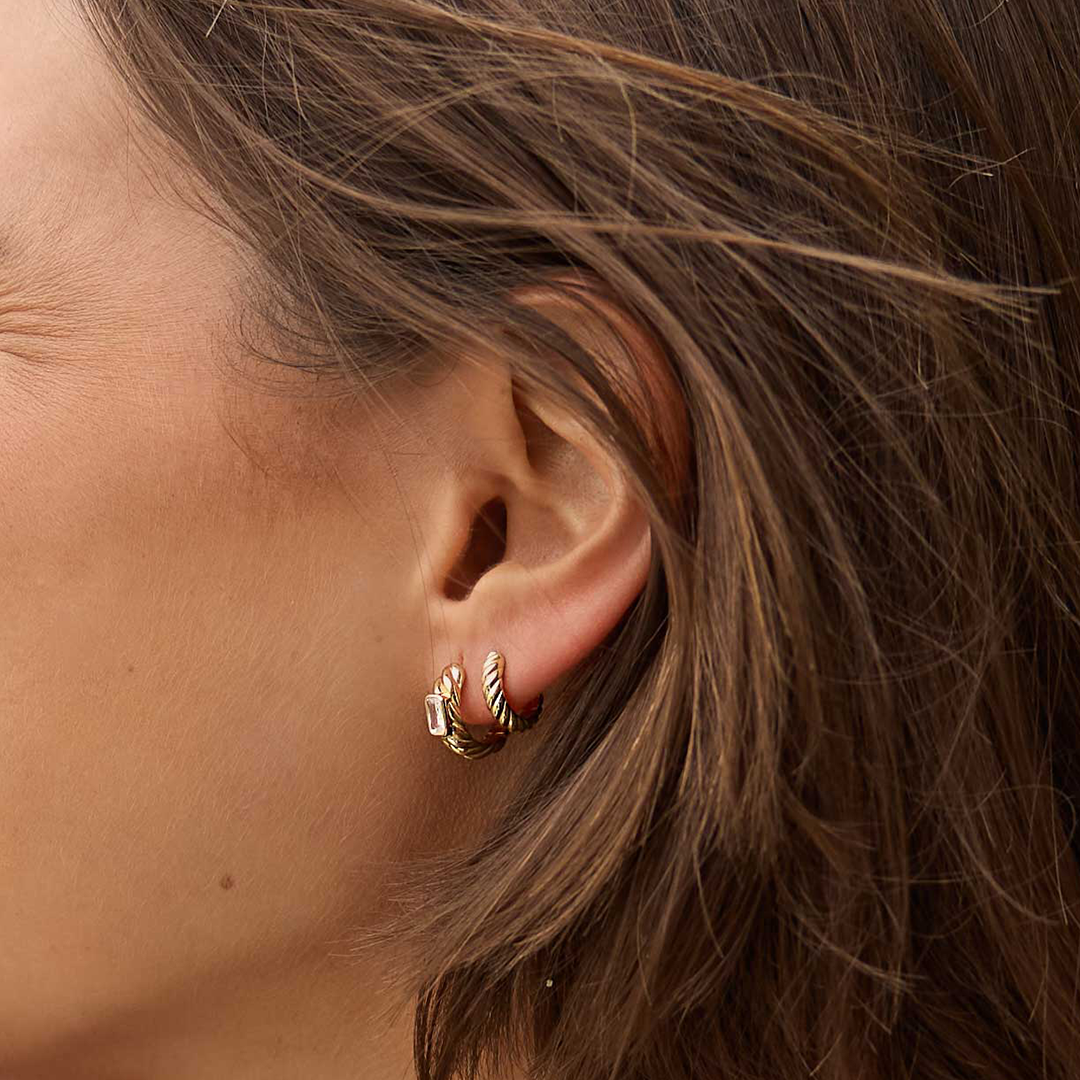 gold delicate huggies with a twist design close up in ears