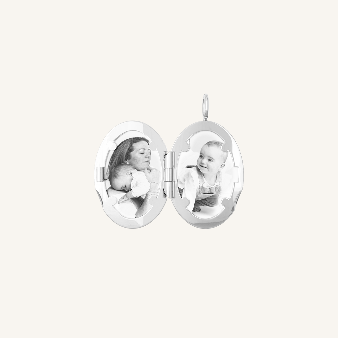 An oval-shaped photo locket with a silver metal tone, open to display two photographs