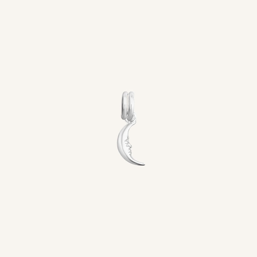 A silver charm in the shape of a crescent moon