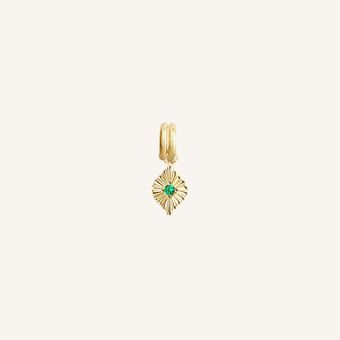 A gold charm with a green cubic zirconia, resembling a May birthstone.