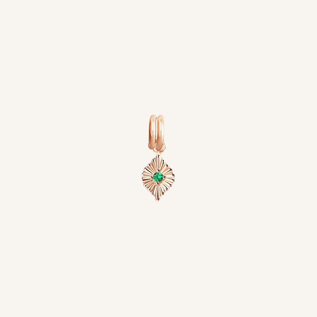 A rose charm with a green cubic zirconia, resembling a May birthstone.