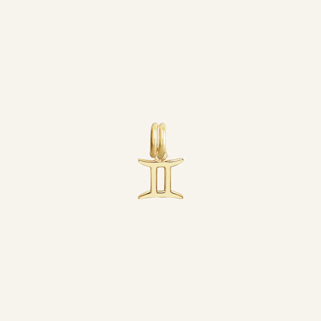 A gold charm representing the Gemini zodiac sign.