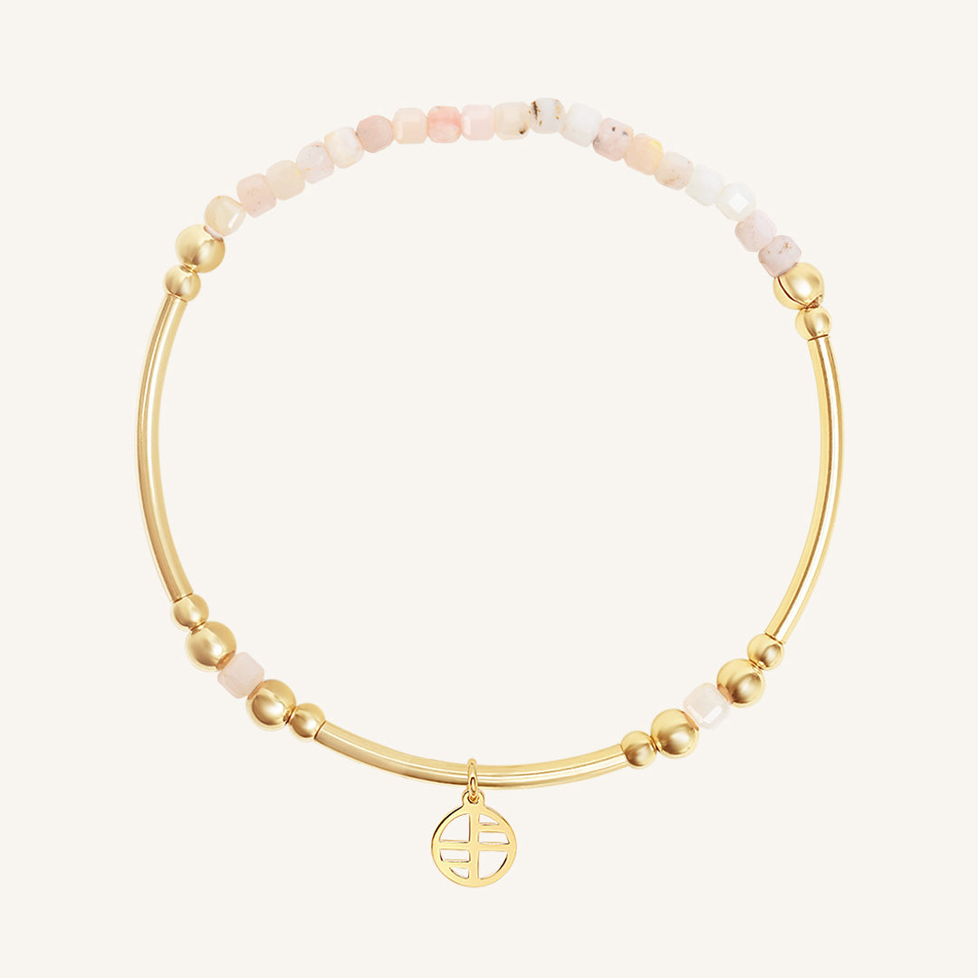 Gold bracelet with pink beads on a white background
