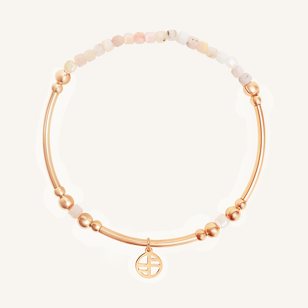 Rose gold bracelet with white beads on a light beige background