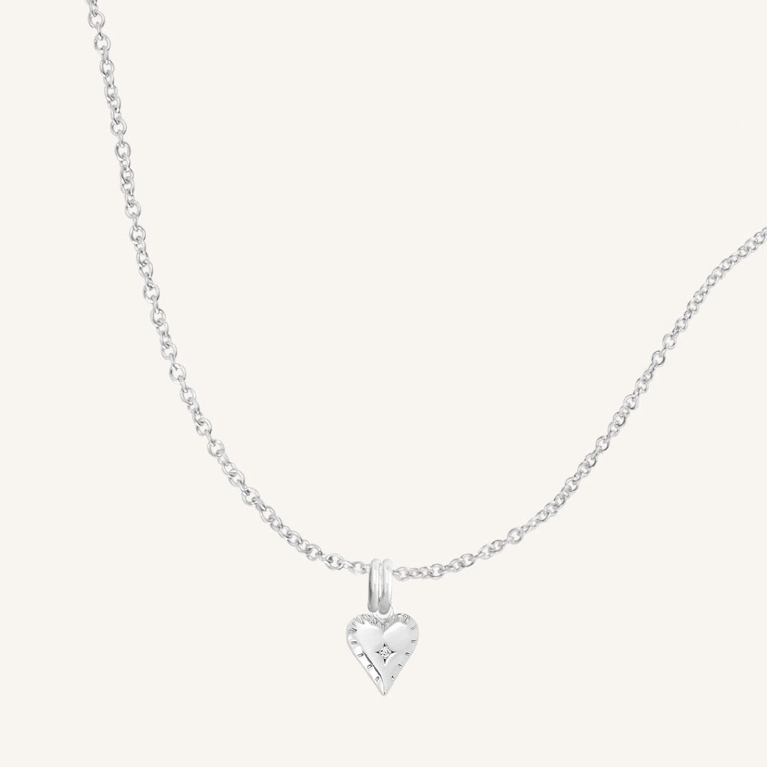 A silver-tone heart-shaped charm necklace with an adjustable chain.