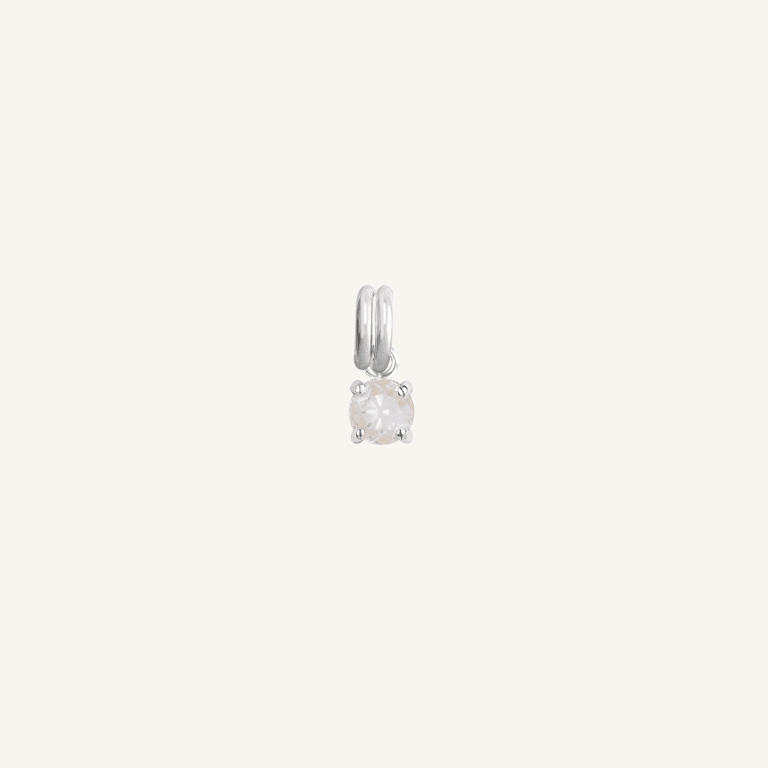 A small silver-colored charm with a moonstone, designed to attach to a bracelet or necklace