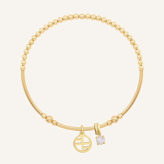 A gold-tone charm bracelet featuring a beaded design with a small circular charm and a moonstone charm.