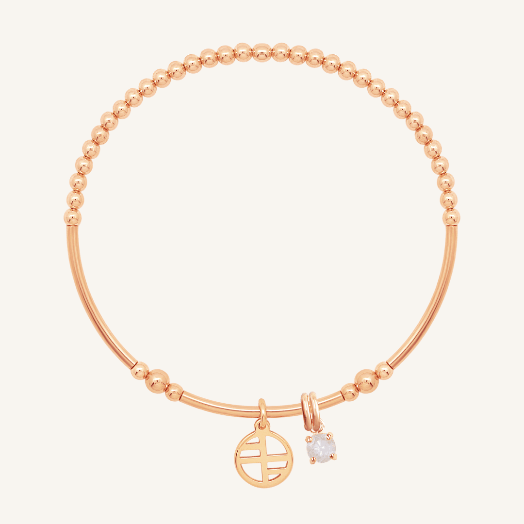 A rose charm bracelet featuring a beaded design with a small circular charm and a moonstone charm.
