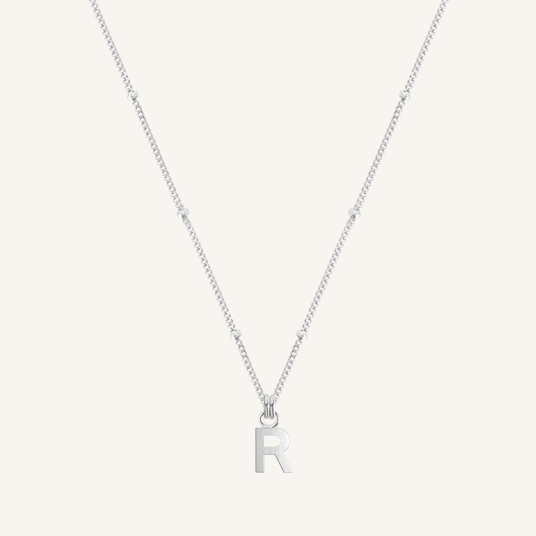 Silver necklace with 'R' pendant on a white background