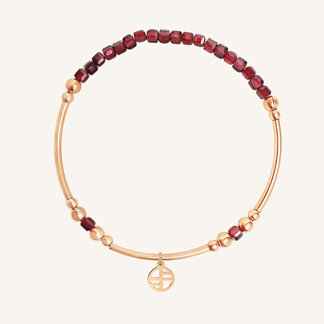 Bracelet with red beads and gold accents on a white background