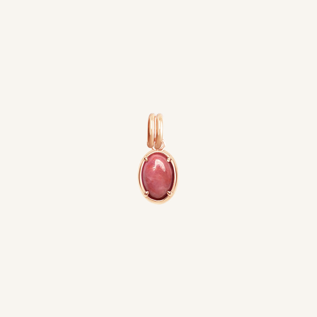 Rose gold charm with a pink gemstone on a white background