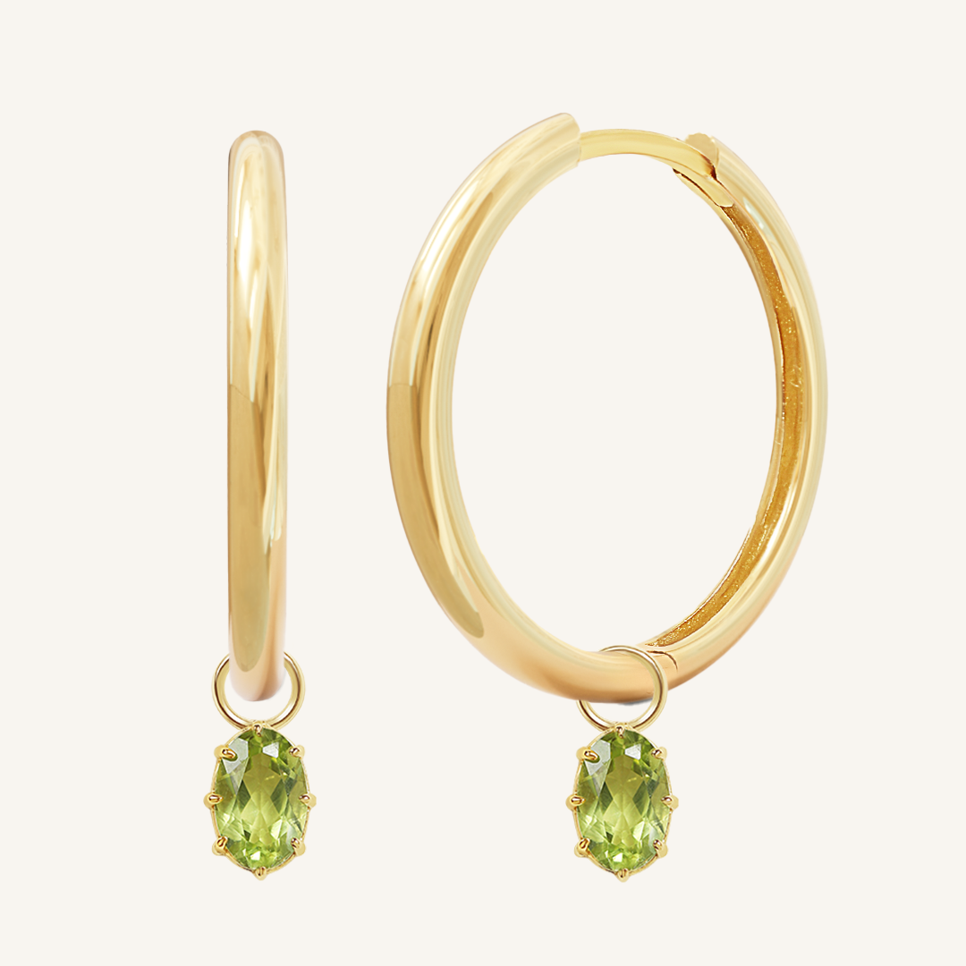 A pair of gold-tone hoop earrings with olive green charms attached to them.