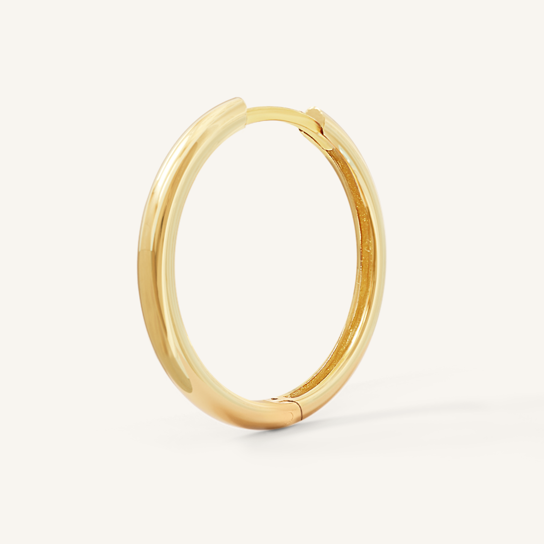 A gold-tone hoop earring on a white background