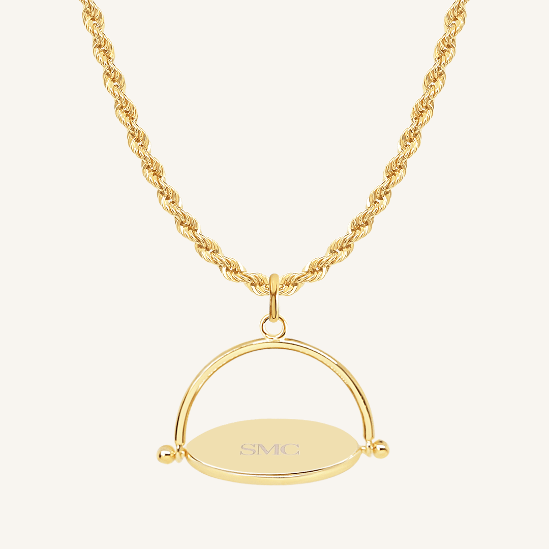 A gold-coloured, engraved pendant with, featuring a spinning mechanism, on chain