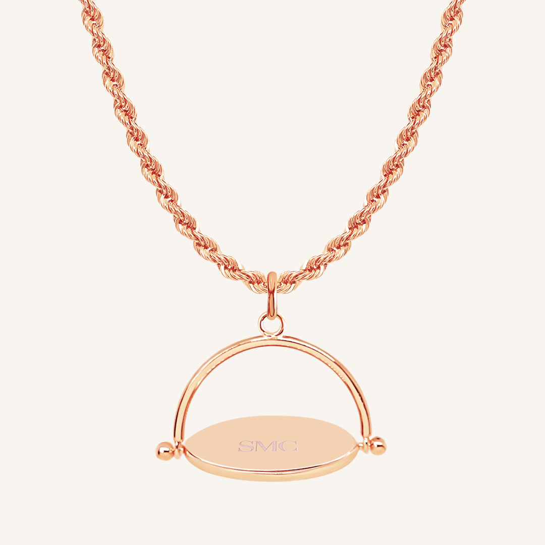 A rose-coloured, engraved pendant with, featuring a spinning mechanism, on chain