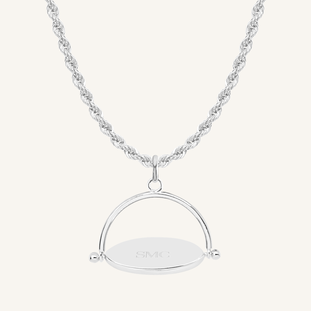 A silver-coloured, engraved pendant with, featuring a spinning mechanism, on chain