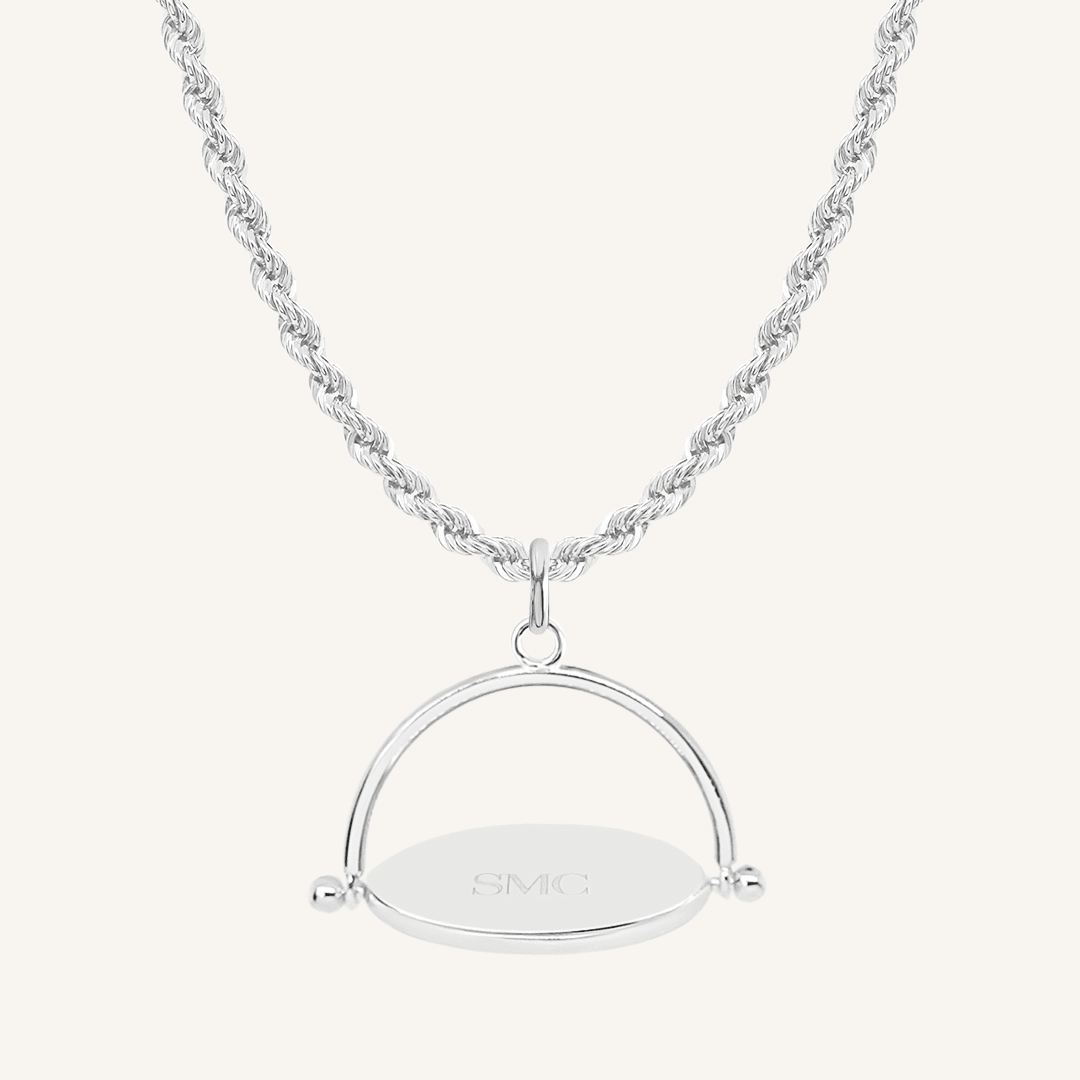 A silver-coloured, engraved pendant with, featuring a spinning mechanism, on chain