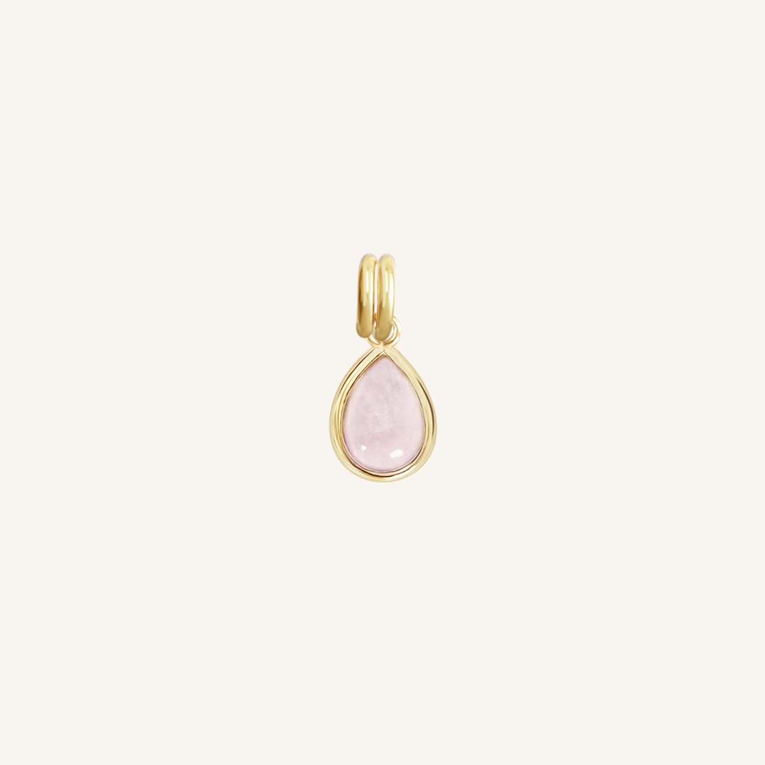 a gold charm with a tear-drop shaped rose quartz stone