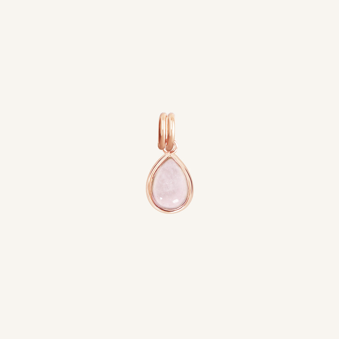 a rose gold charm with a tear-drop shaped rose quartz stone