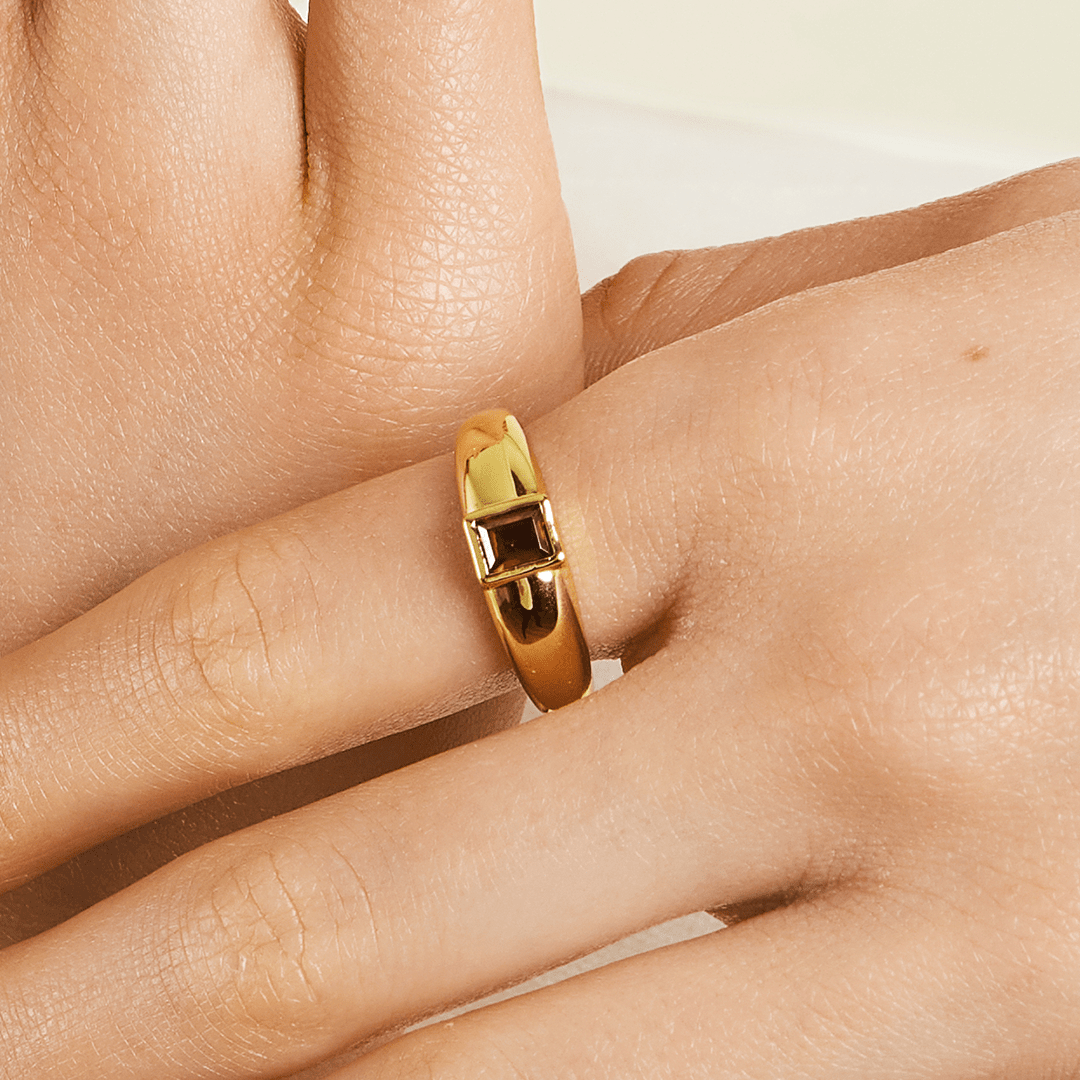 gold ring inspired by the city of love with a deep red square cubic zirconia bezel set on white background