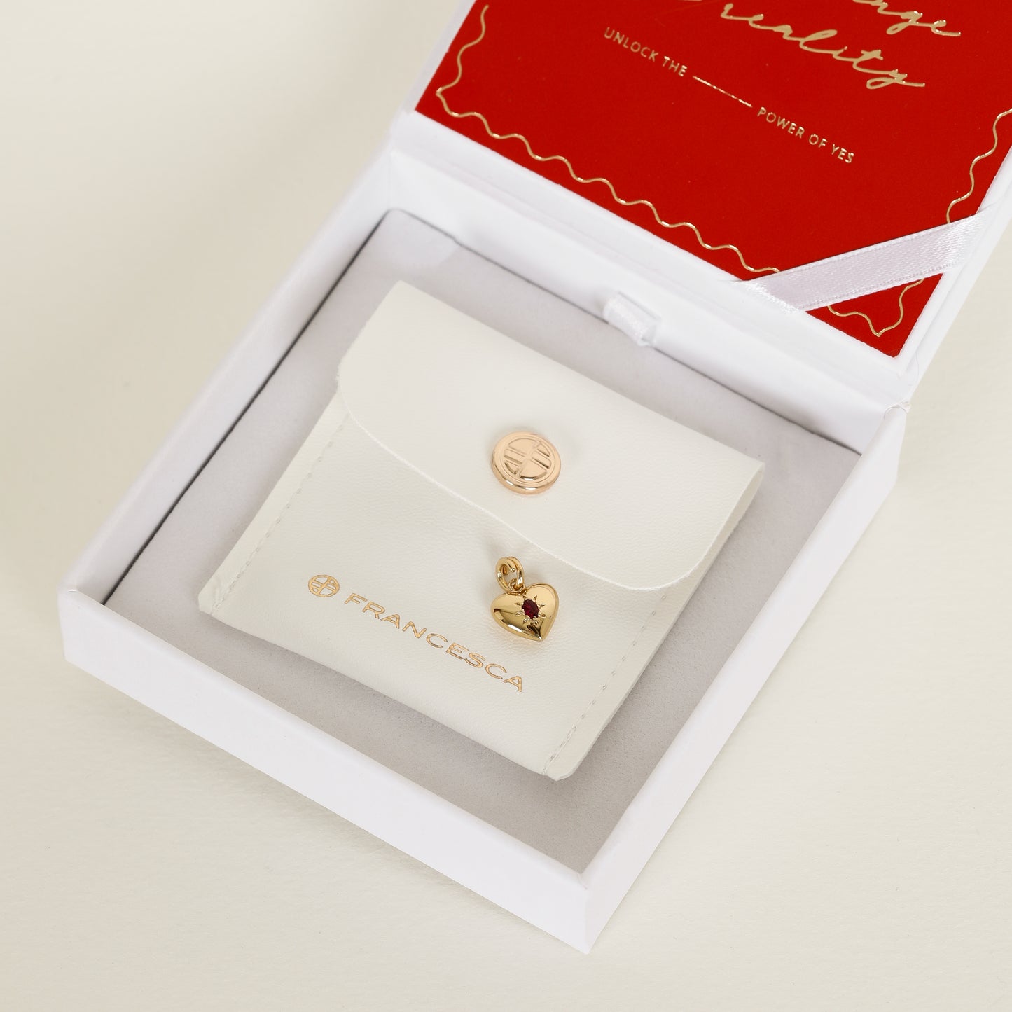 gold heart shaped charm with deep red oval cubic zirconia in white n
box with pouch