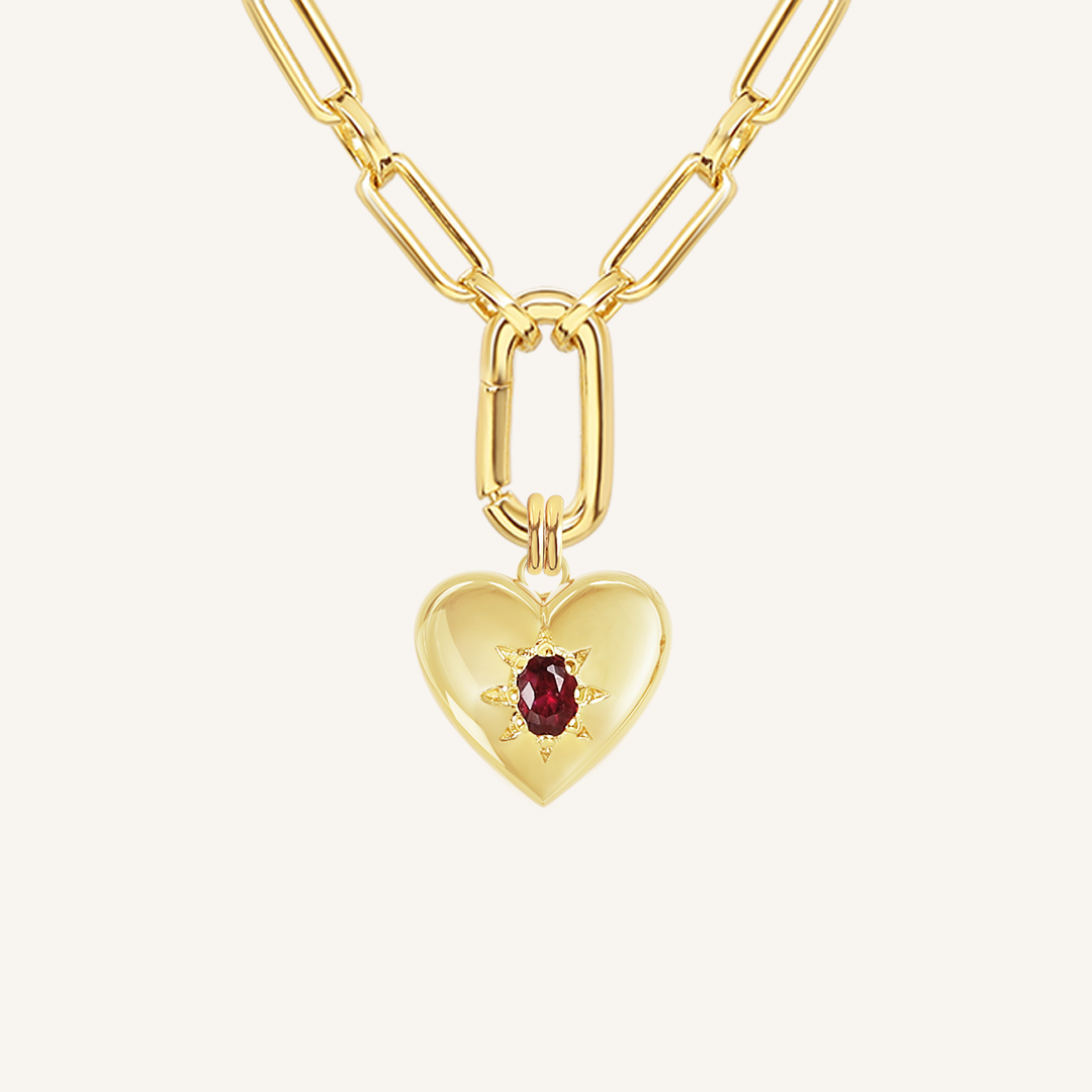 gold heart shaped charm with deep red oval cubic zirconia on link chain on white background