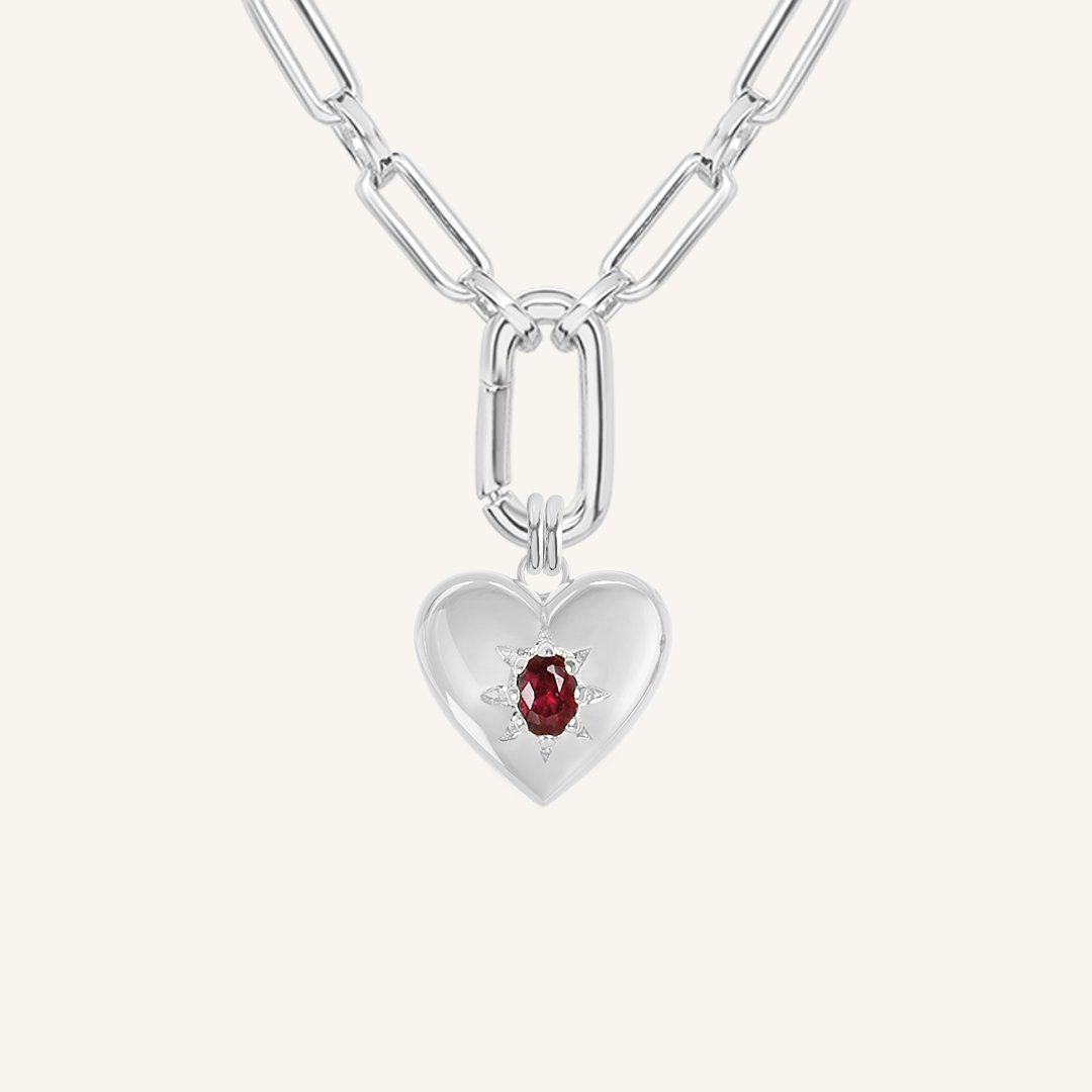 silver heart shaped charm with deep red oval cubic zirconia on link chain on white background