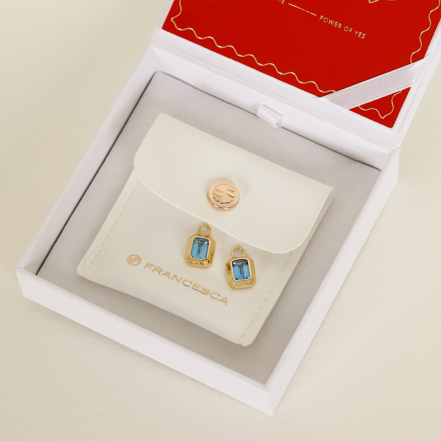 rectangular gold hoop charms with Blue emerald cut cubic zirconias bezel set on white box