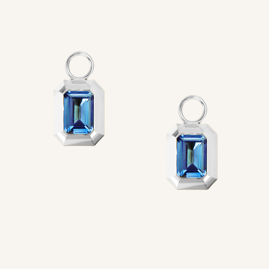 rectangular silver hoop charms with Blue emerald cut cubic zirconias bezel set on white background